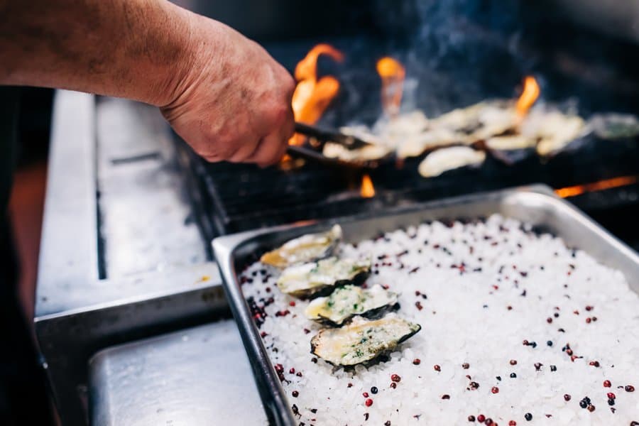 Chef grilling oysters over open flame